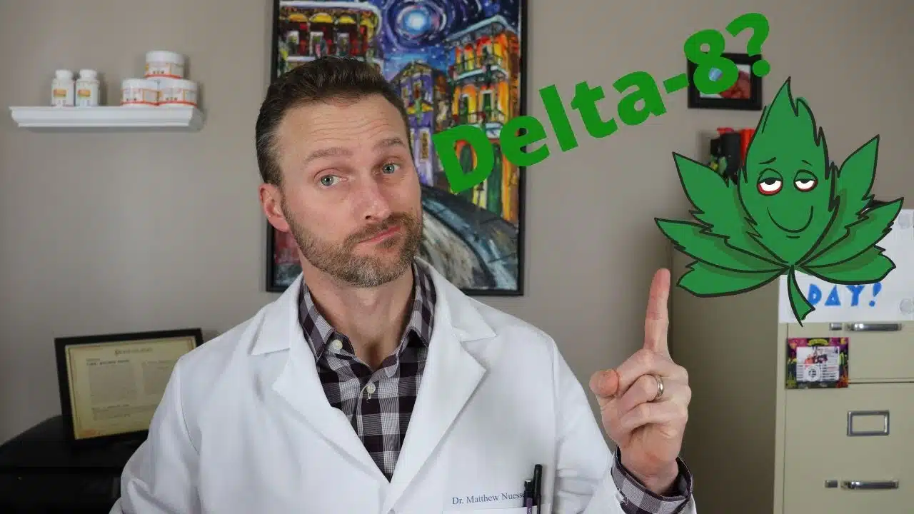 A man in a lab coat is pointing to a CBD leaf, explaining why Delta 8 is legal.