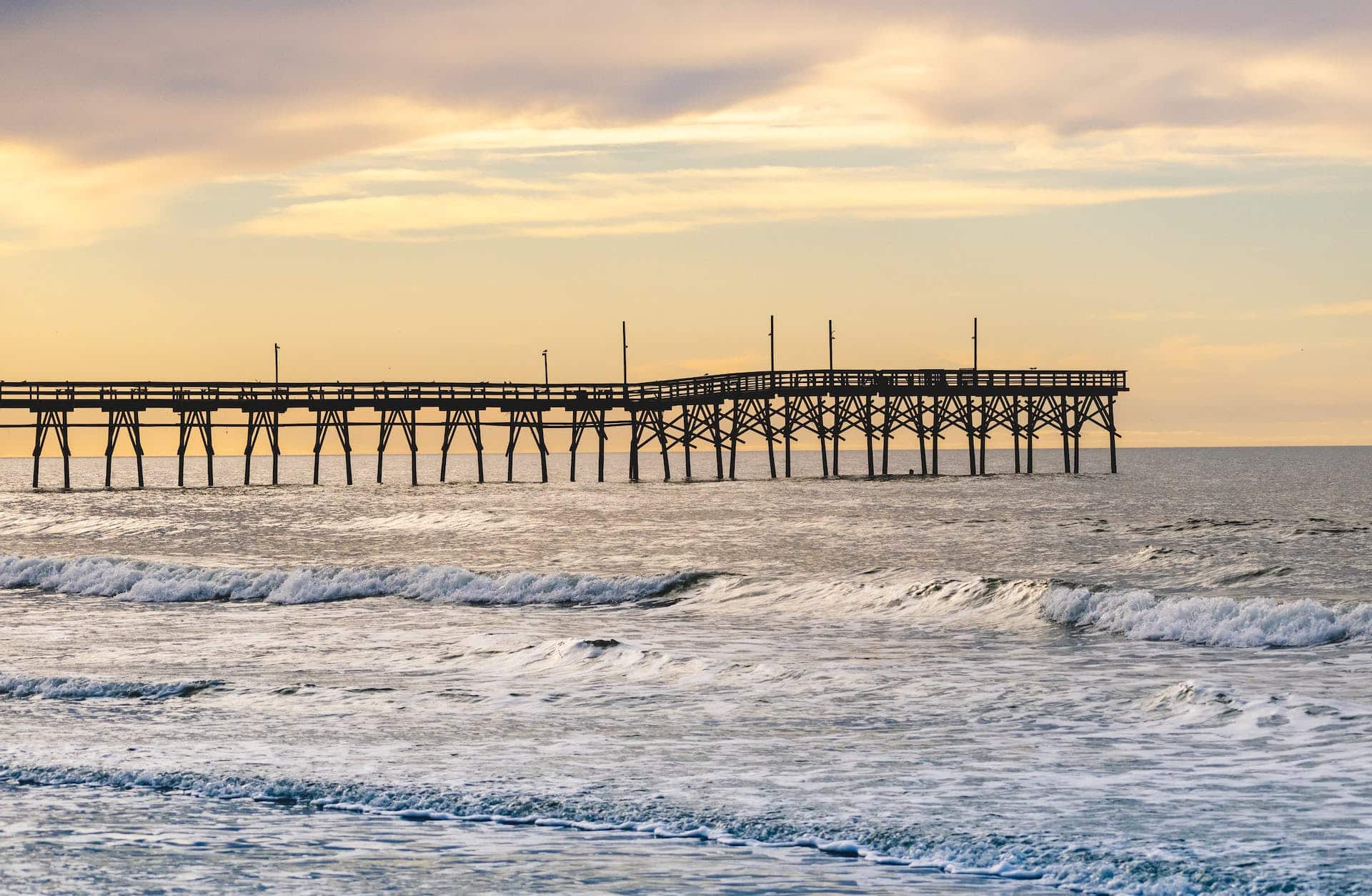 A pier in the ocean with waves crashing over it, located in NC.