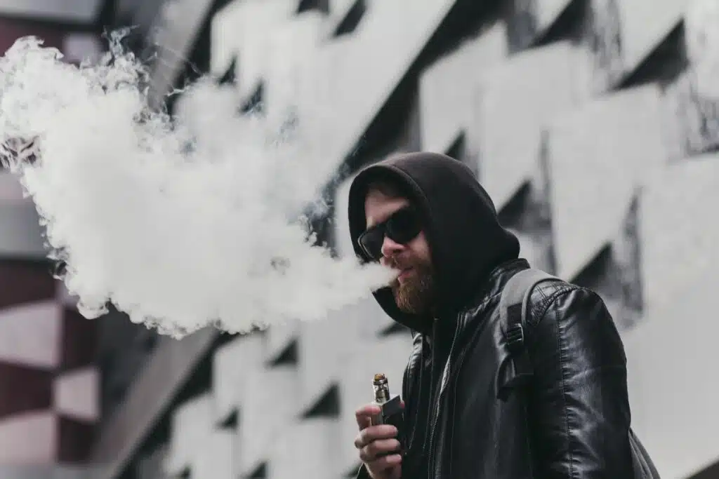 A guy vaping and blowing clouds