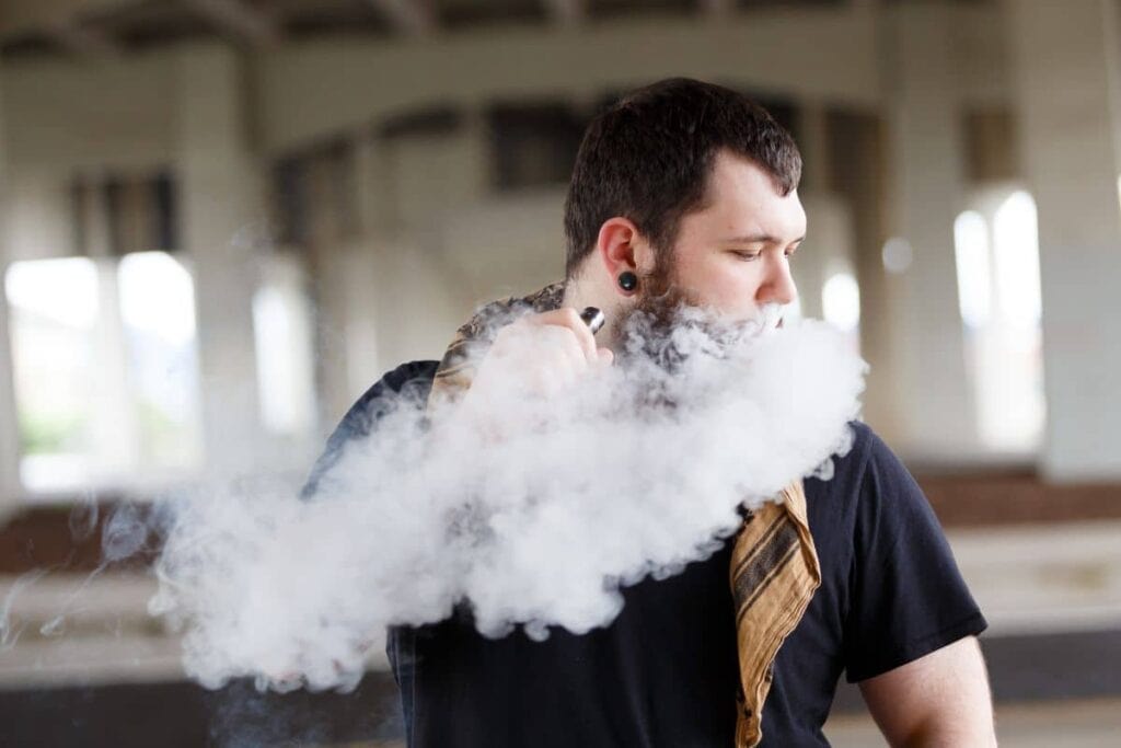 A guy vaping a 3chi disposable in a parking lot