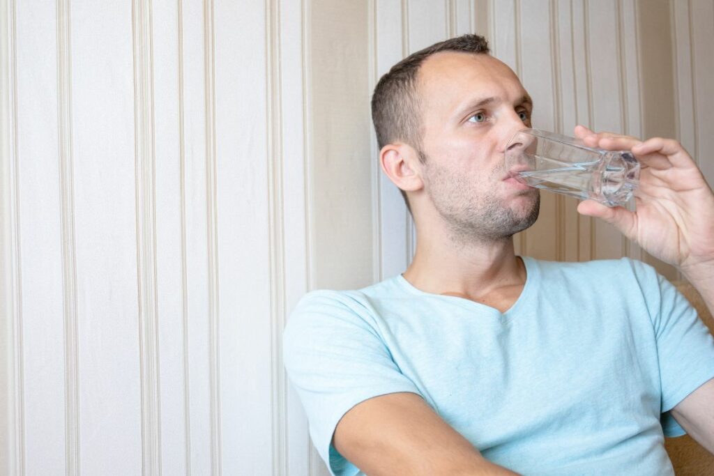 A guy drinking water and Detoxing from delta 8 thc