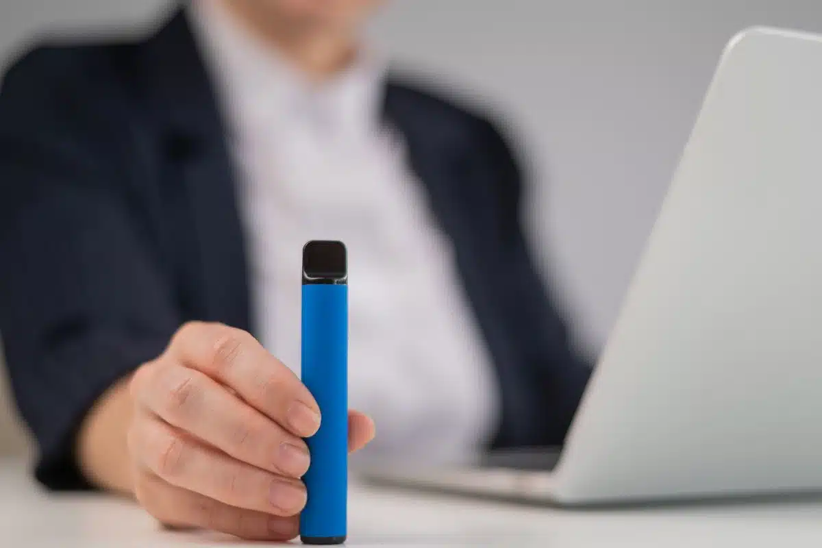 A woman holding delta 8 disposable vape device in her hand