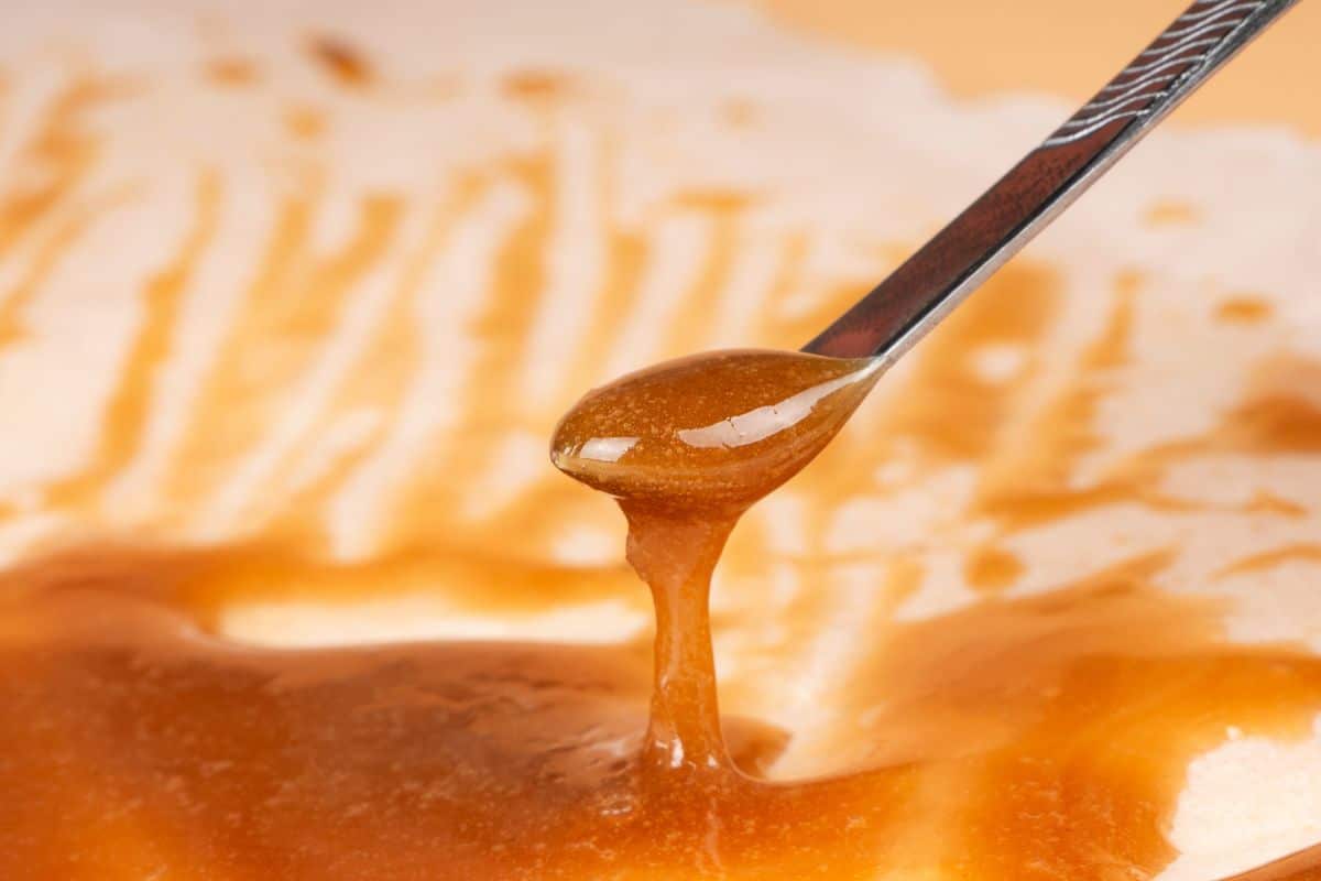 A spoon is pouring hash rosin into a bowl.