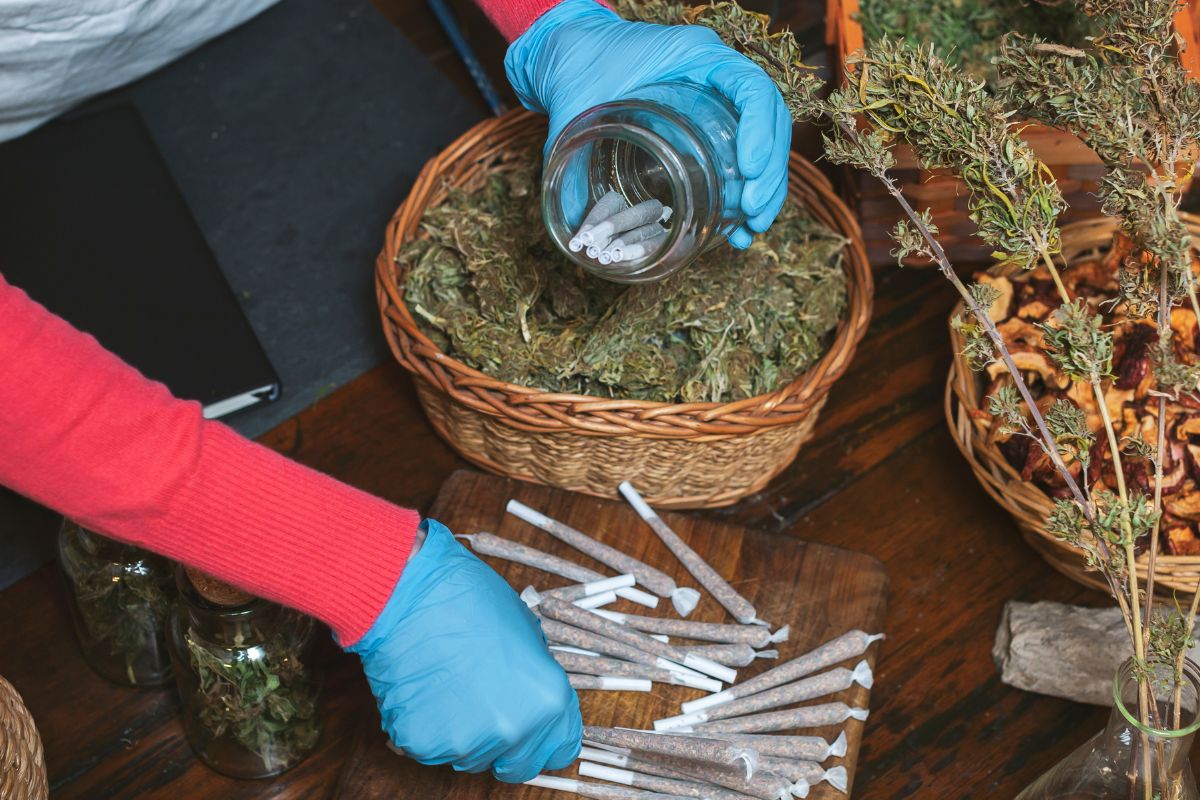 A woman storing cannabis pre rolls in a glass jar