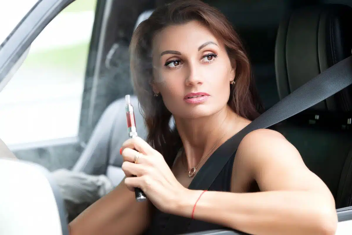 A girl vaping and driving a car