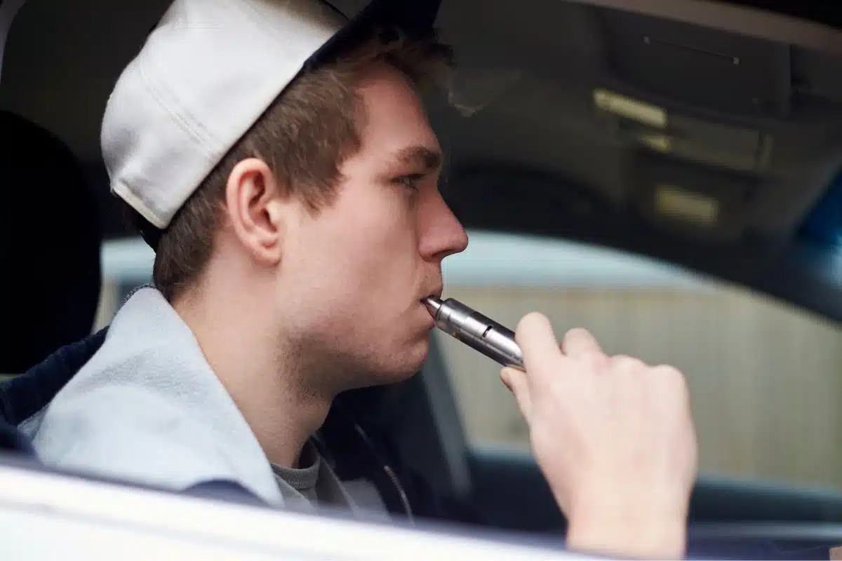 A guy using vaping device inside a car