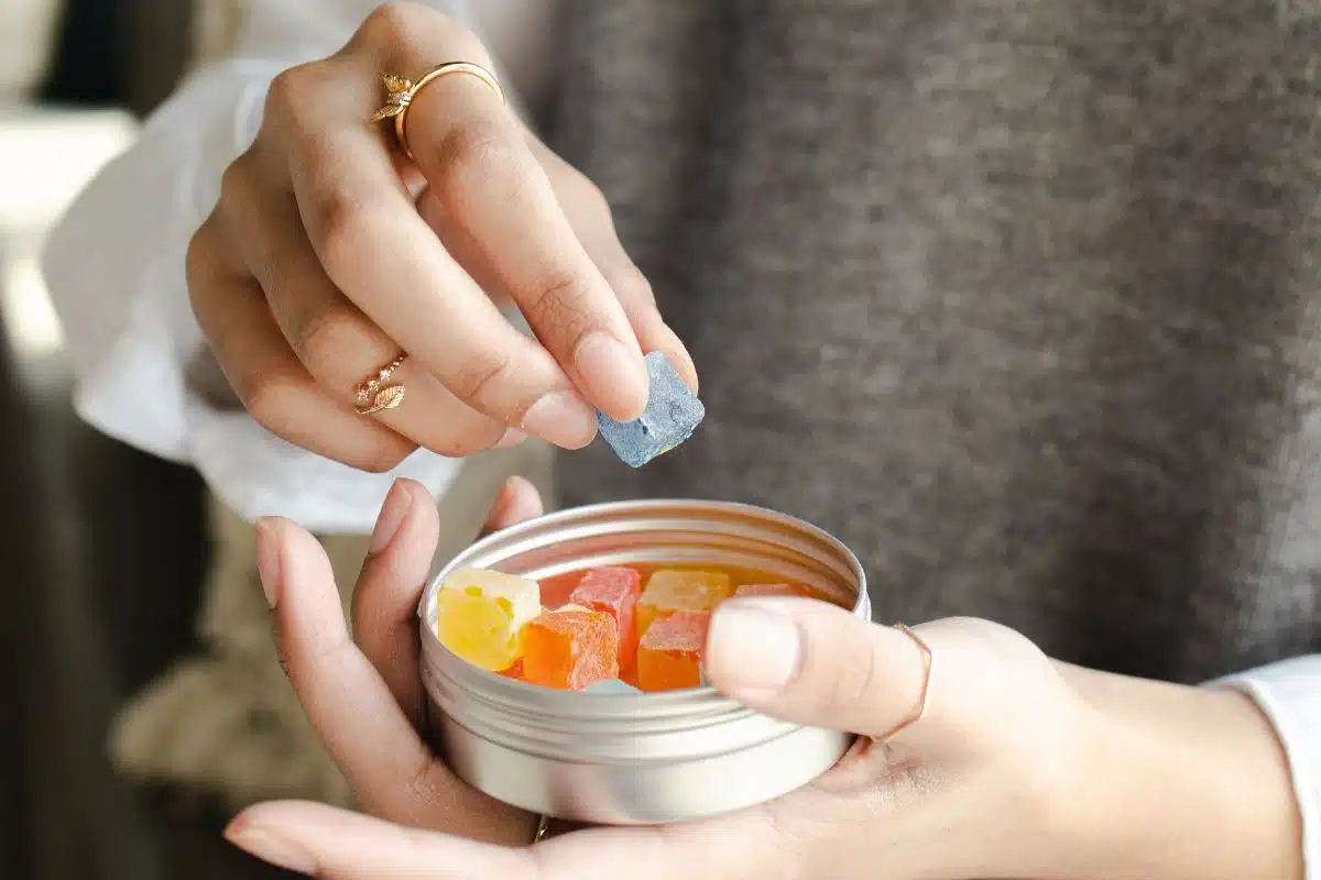 A woman holding a tin of gummy bears, featuring sativa gummies.