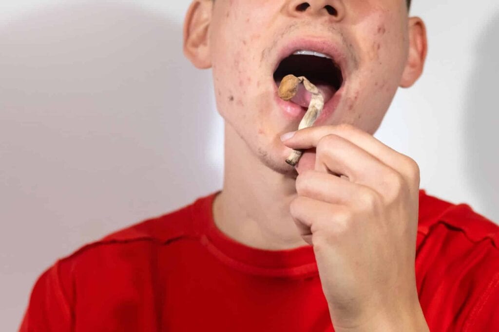 A man putting magic mushroom in his mouth
