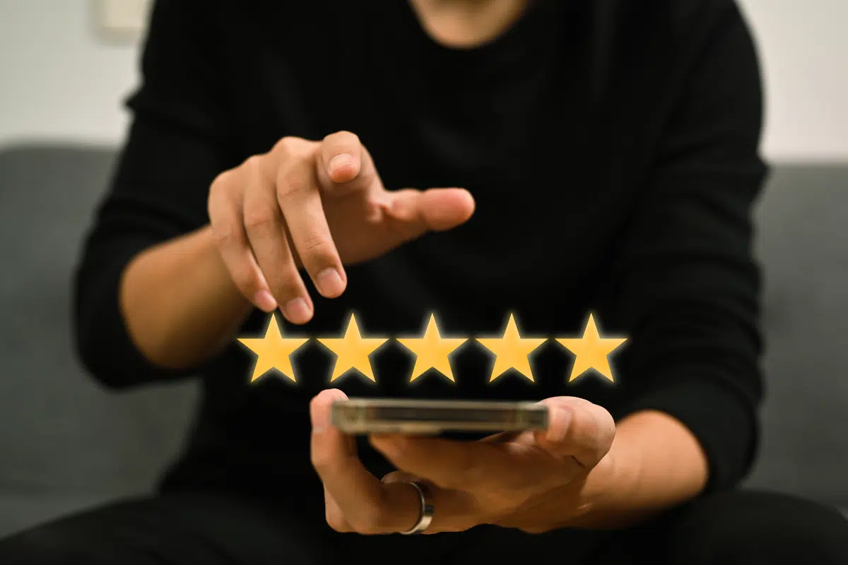 A man holding a smartphone displaying five stars.