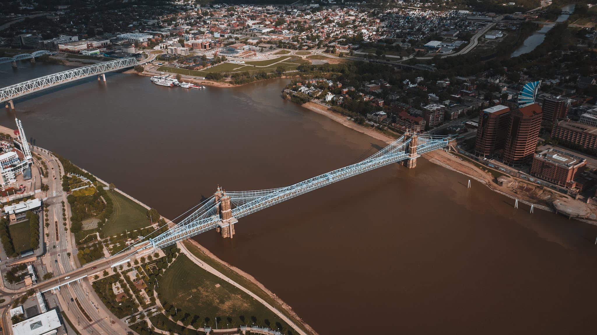 From above of city view and John Roebling Suspension Bridge crossing river with muddy water located in ohio USA