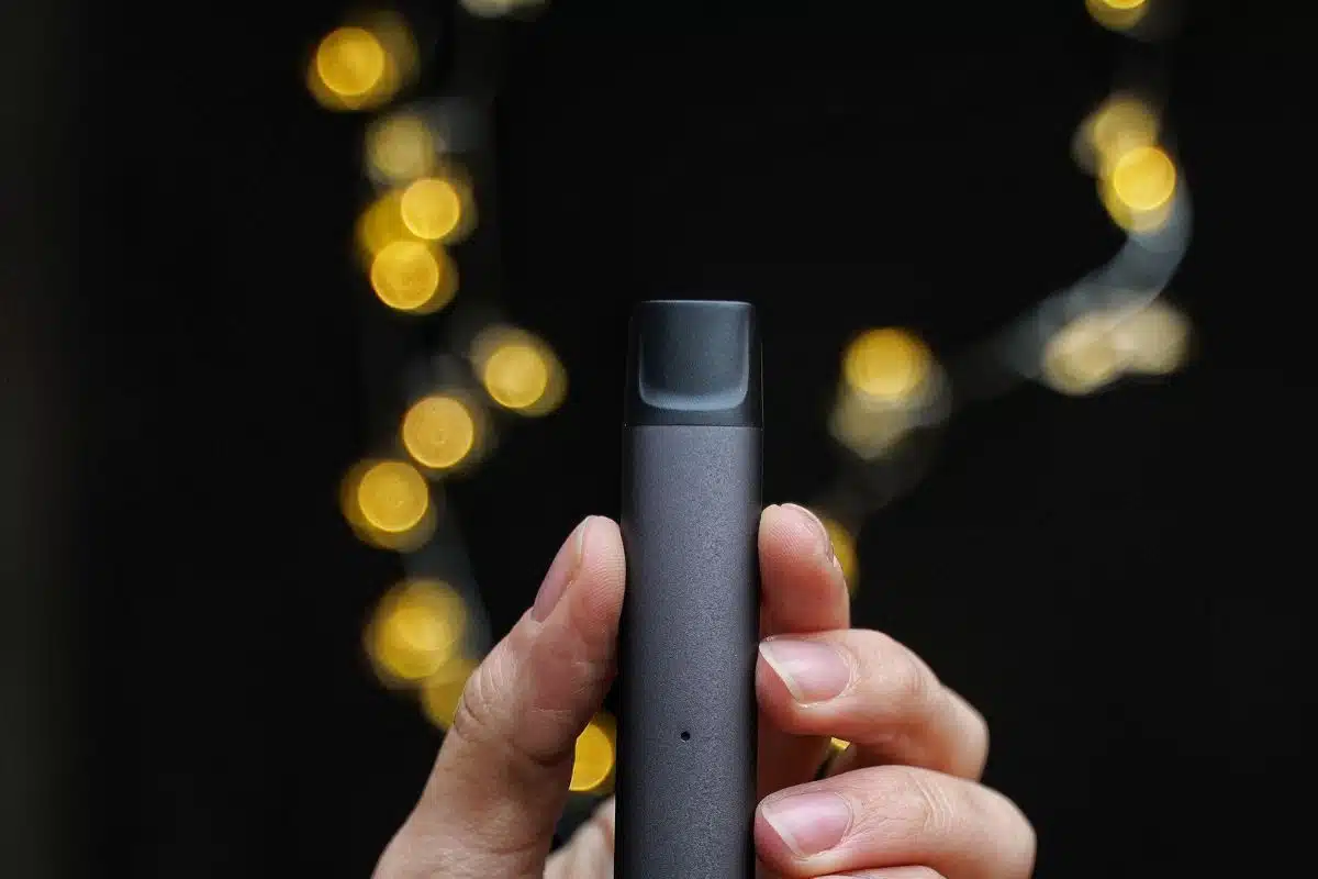 A guy holding 3chi vape pod in his hand