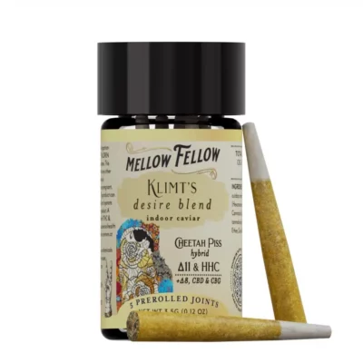 A 3.5g jar of Mellow Fellow Klimt's Desire Blend Indoor Caviar Pre-Rolls, labeled as a Cheetah Piss hybrid with Δ11 & HHC +Δ8, CBD & CBG, with two joints lying beside it.