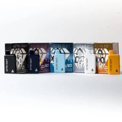 A row of Astro Eight vape cartridges in various colors, including black, purple, blue, white, and orange, placed in front of matching packaging. The design features a geometric logo and text on each cartridge and box.