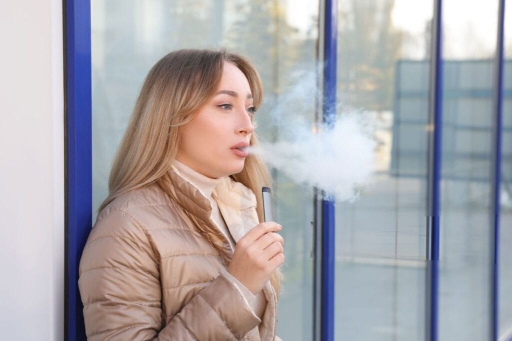 A lady is using a disposable vape