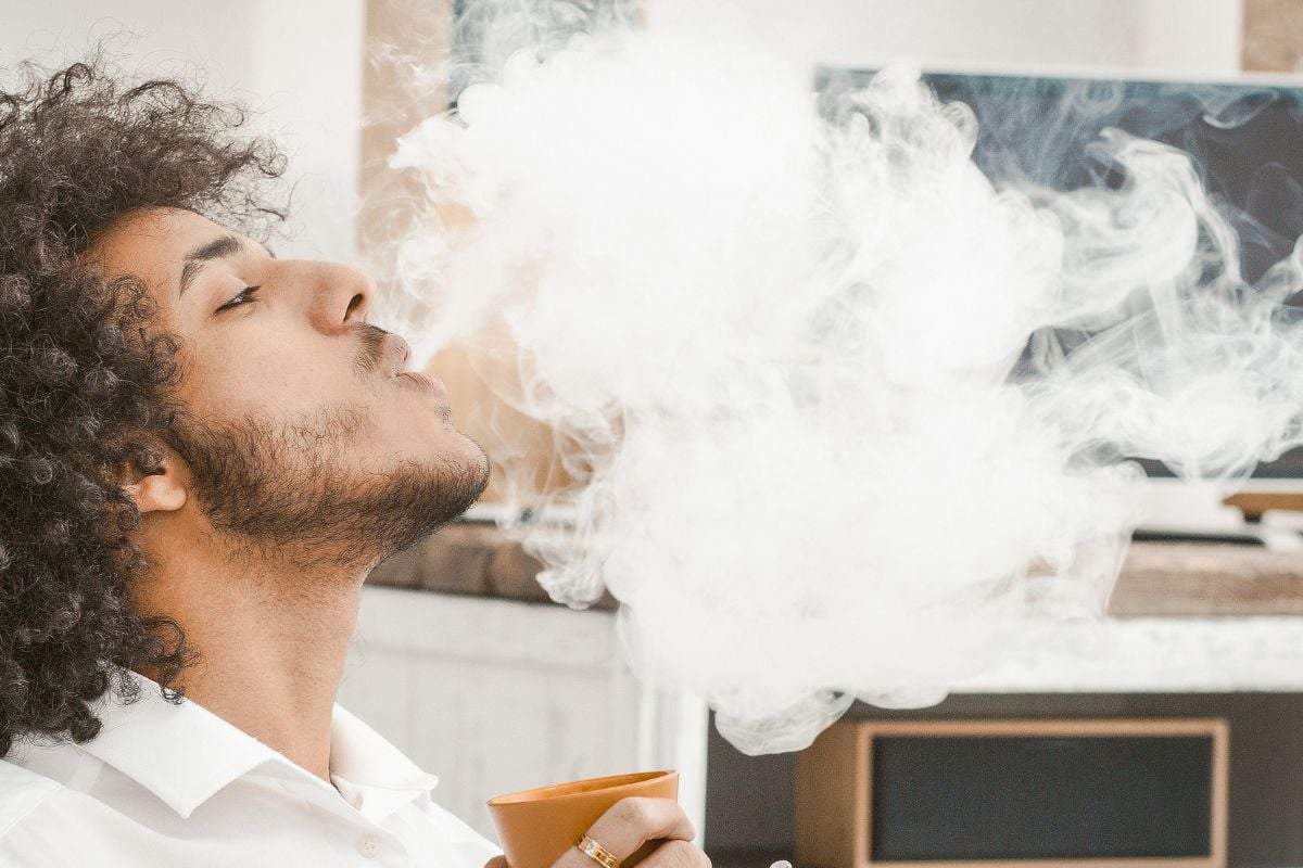 A person vaping a Raz vape and drinking coffee