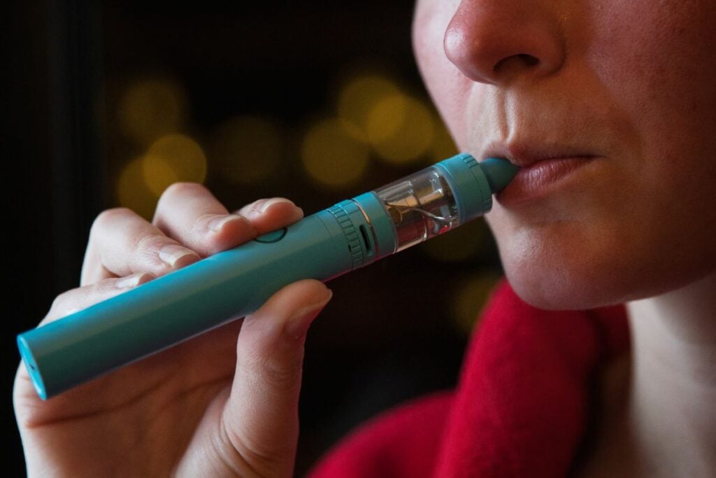 A person vaping through a cart containing THC liquid in it