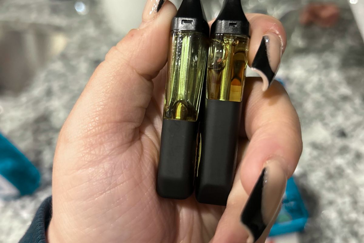 A women holding muha meds vape fake one on the right side and real one on the left side