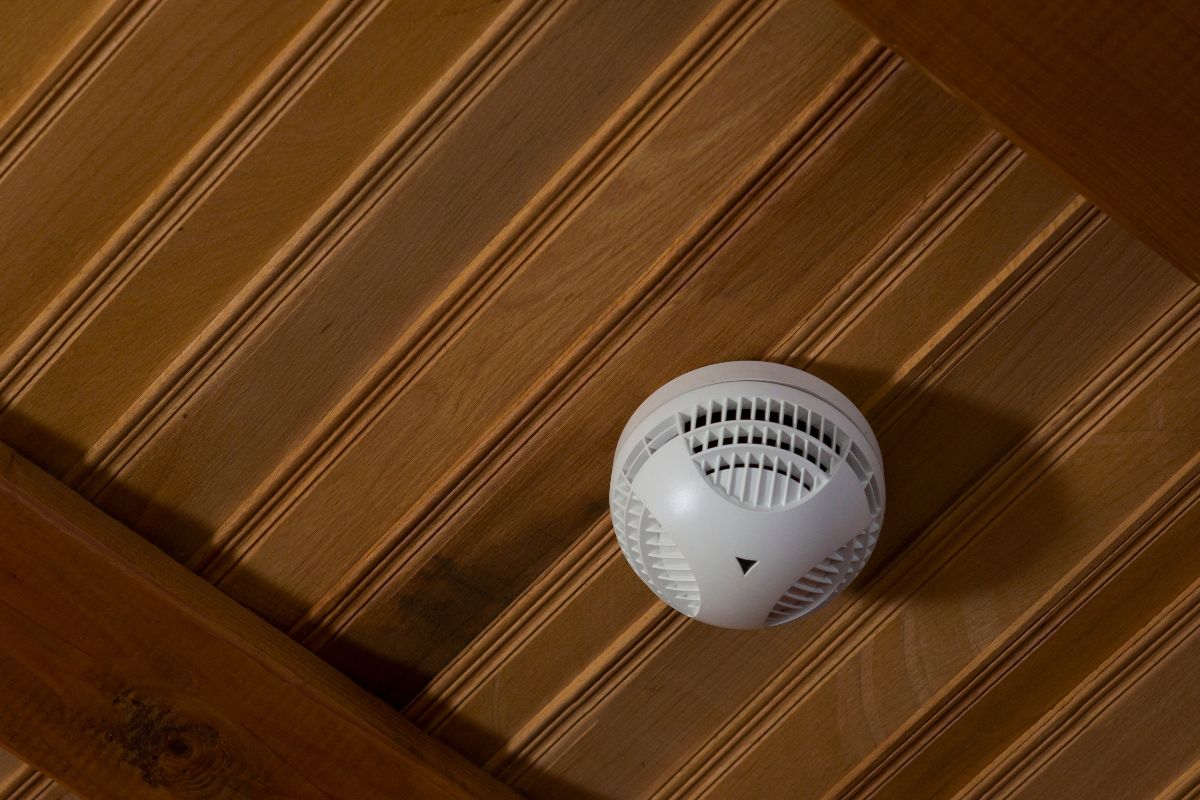 A smoke detector is shown on the ceiling of a hotel in the image